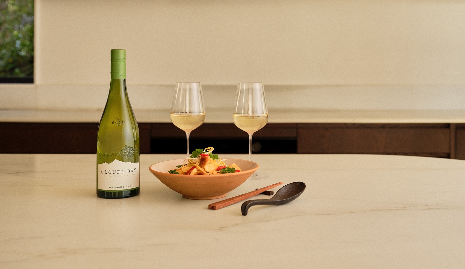 Table with sauvignon blanc glasses and plate of dumplings and noodles